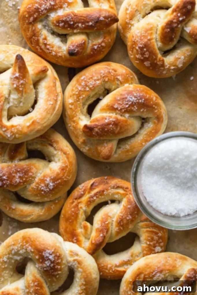Overhead view of soft baked pretzels next to a dish of salt. 