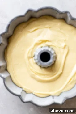 The rich, pale yellow pound cake batter perfectly poured into a greased and floured Bundt pan, ready to be baked to a golden perfection. The smooth surface of the batter is evenly spread.