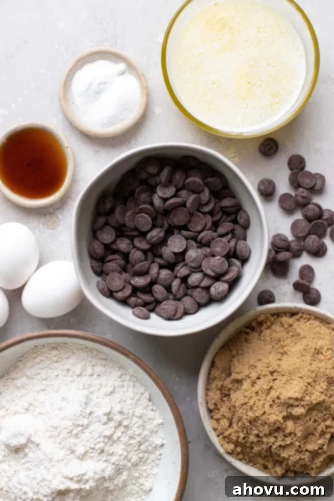 An overhead shot of all the essential ingredients laid out for making delicious chocolate chip bar cookies, including butter, sugar, flour, eggs, and chocolate chips.