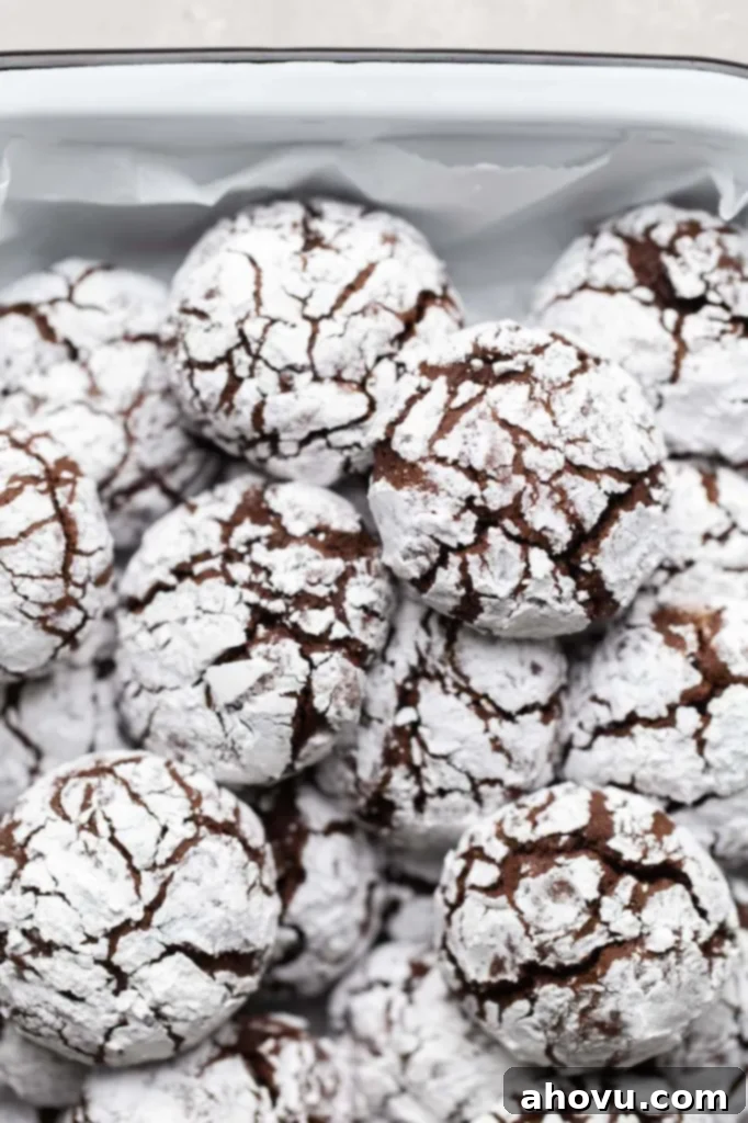 Several chocolate crinkle cookies piled on top of each other in a white dish.