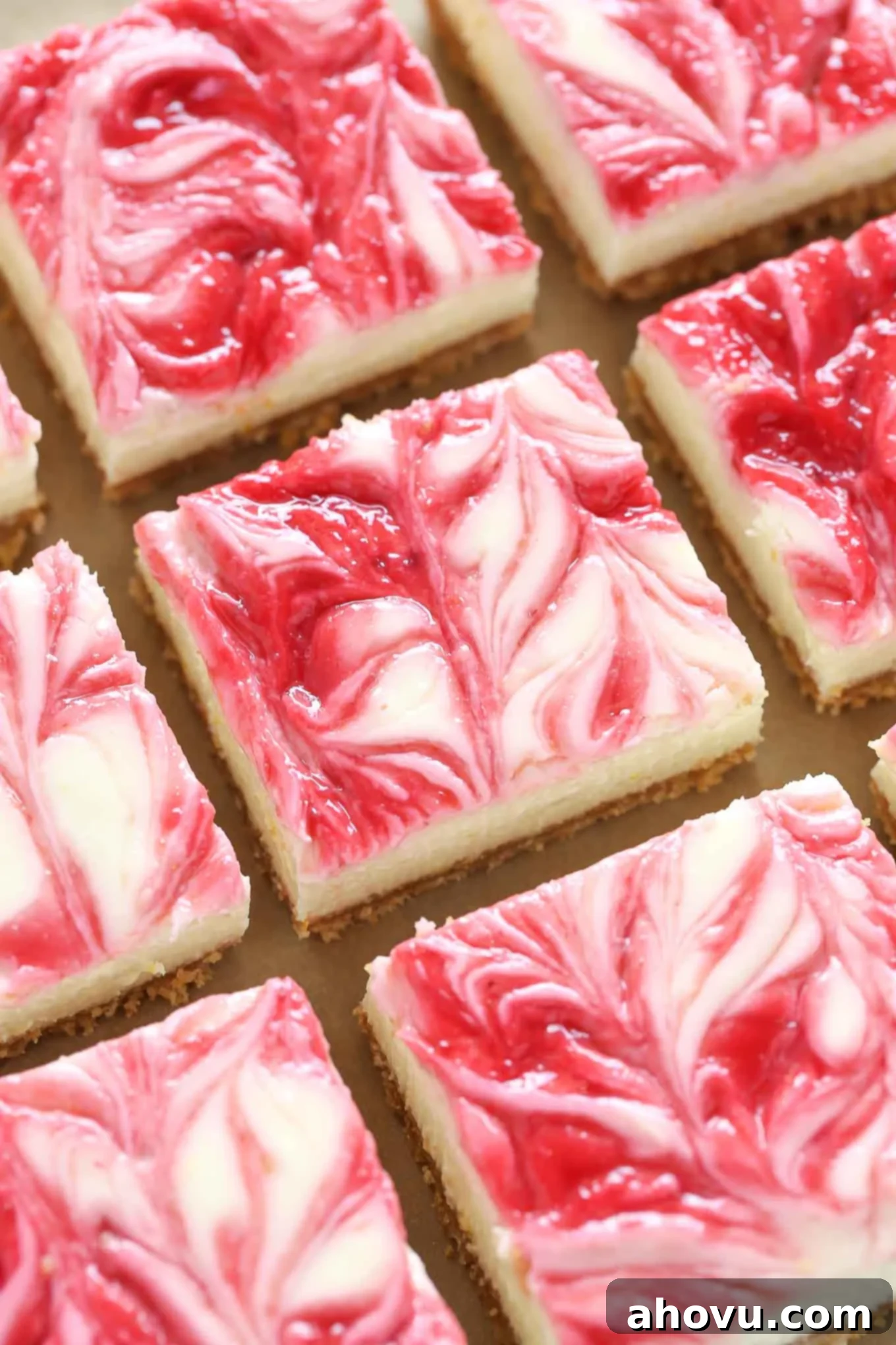 Overhead view of lemon raspberry cheesecake lined up in rows. 