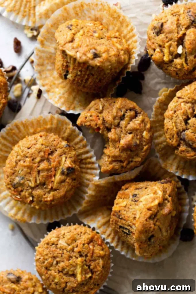 Overhead view of morning glory muffins in muffin liners on a wire cooling rack. Some of the muffins are turned on their sides, and one has a bite missing. 