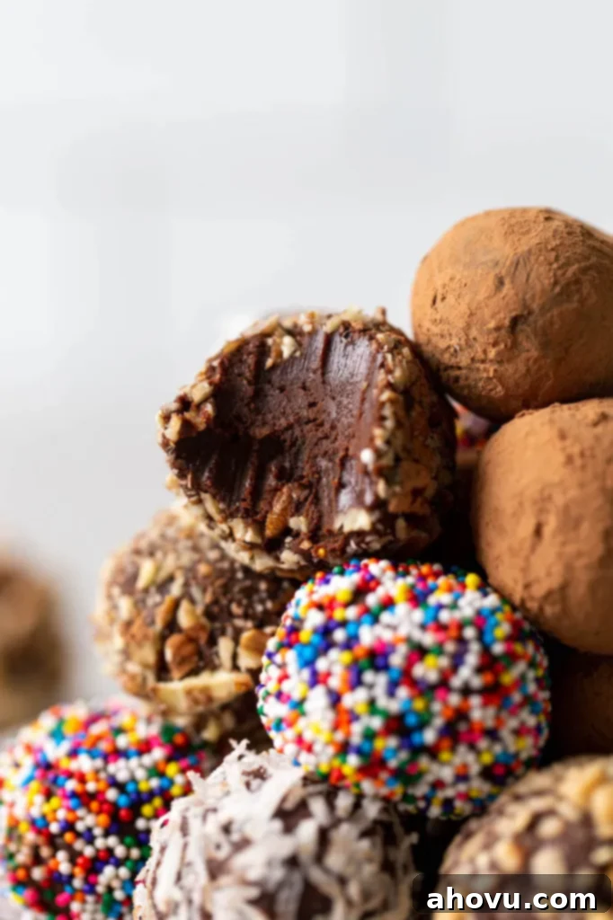 A close-up view of a small pile of homemade chocolate truffles, with one truffle showing a bite taken out, revealing its smooth, rich interior.