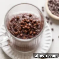 Decadent Mug Brownie 7 Overhead view of a microwave mug brownie in a glass mug. The mug sits on a white dessert plate, and a dish of mini chocolate chips rests on the side.