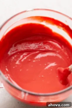 A glass mixing bowl filled with red velvet cake cheesecake batter.