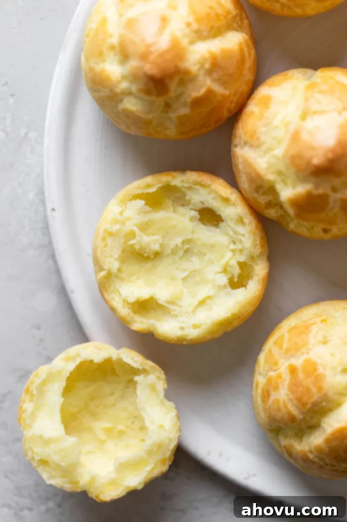 Overhead view of unfilled cream puff shells. One shell has been split in half. 