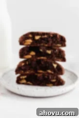 A stack of thick chocolate cookies with peanut butter chips on a white plate. Decadent, chewy chocolate cookies loaded with rich peanut butter chips.