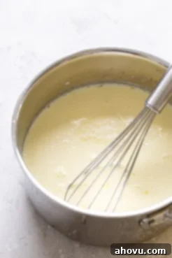 A saucepan filled with vanilla pudding. A whisk rests in the saucepan.