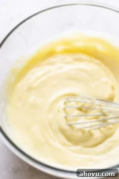 Chilled vanilla pudding in a glass bowl with a whisk.