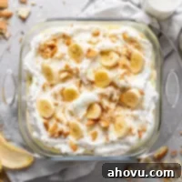 Overhead view of a baking dish filled with banana pudding from scratch. Crushed Nilla Wafers and a banana peel surround the baking dish.