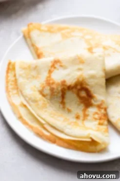 Three homemade crepes on a white plate.