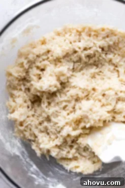 Coconut macaroon dough in a glass mixing bowl with a rubber spatula, showing the perfect sticky consistency.