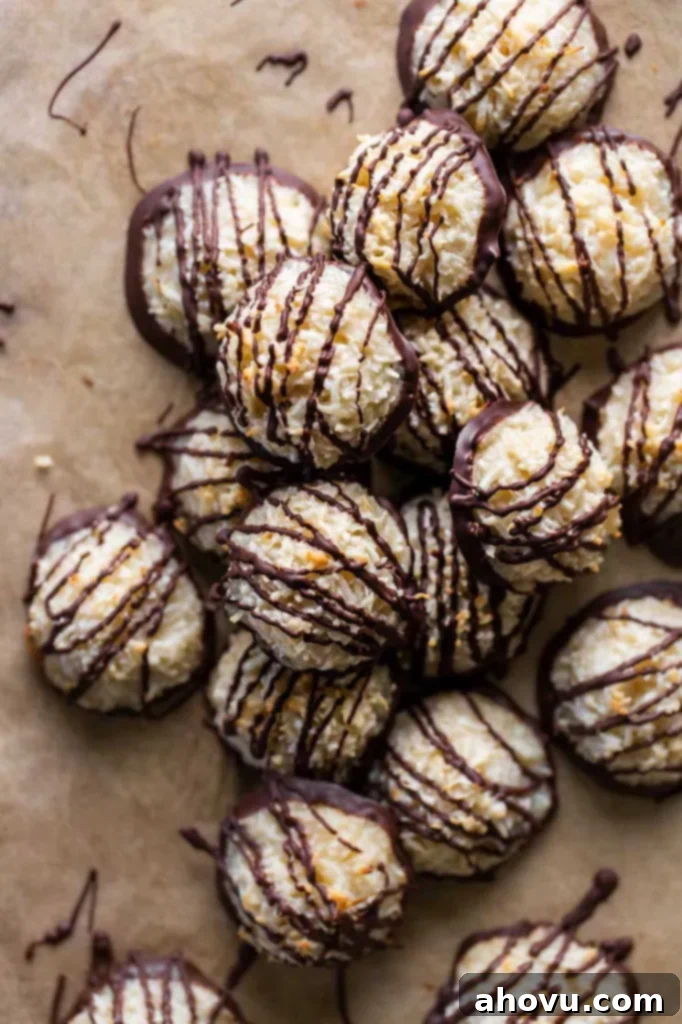 A pile of macaroon cookies drizzled with chocolate on parchment paper, perfectly set.