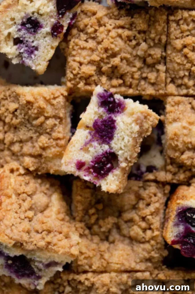 Blueberry Burst Coffee Cake 2 An overhead view of a sliced blueberry coffee cake with some slices turned on their side, revealing the moist interior and blueberries.