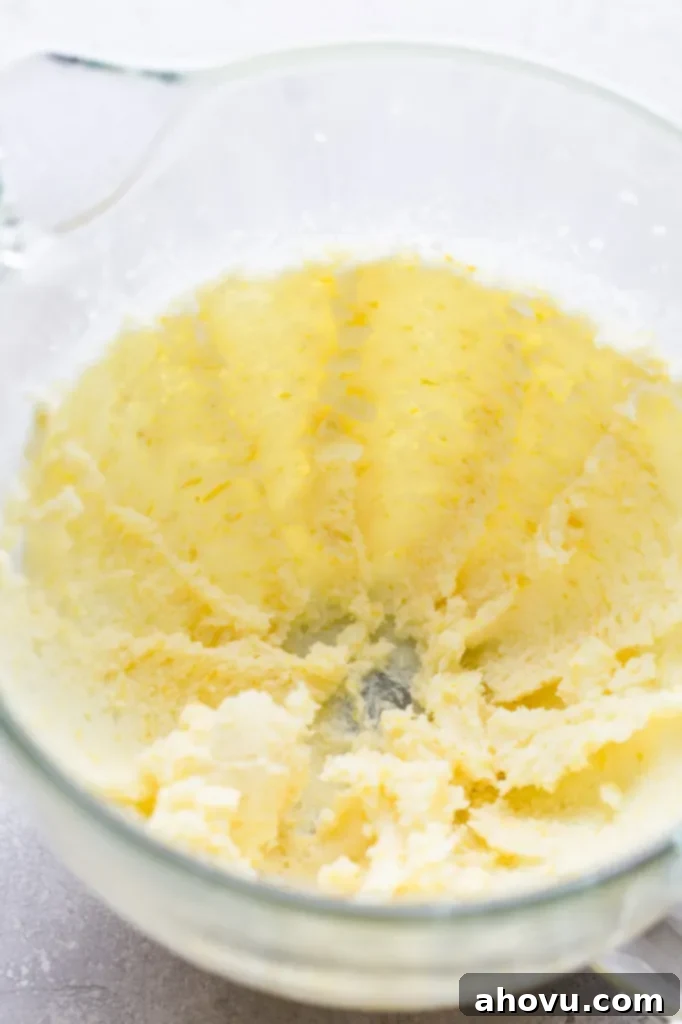 A glass mixing bowl with creamed butter and sugar. 