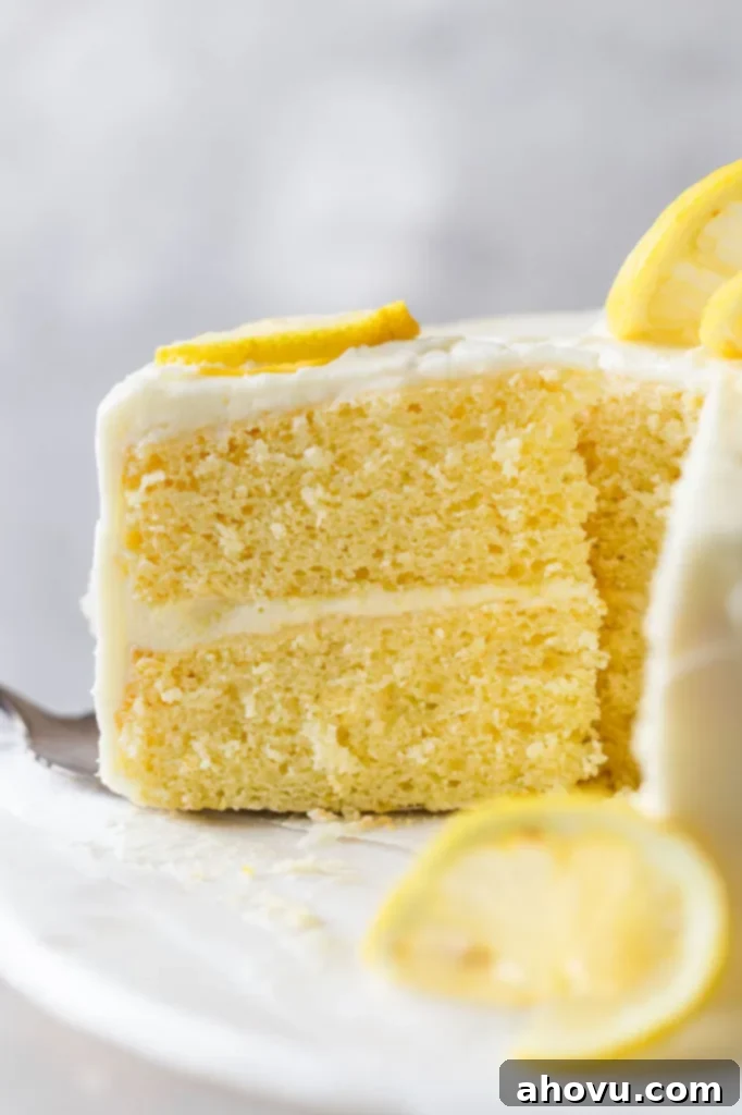 A side view of a slice of lemon cake being removed from a cake stand. 