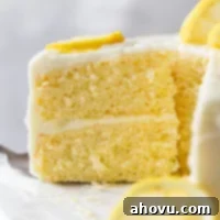 A side view of a slice of lemon cake being removed from a cake stand.