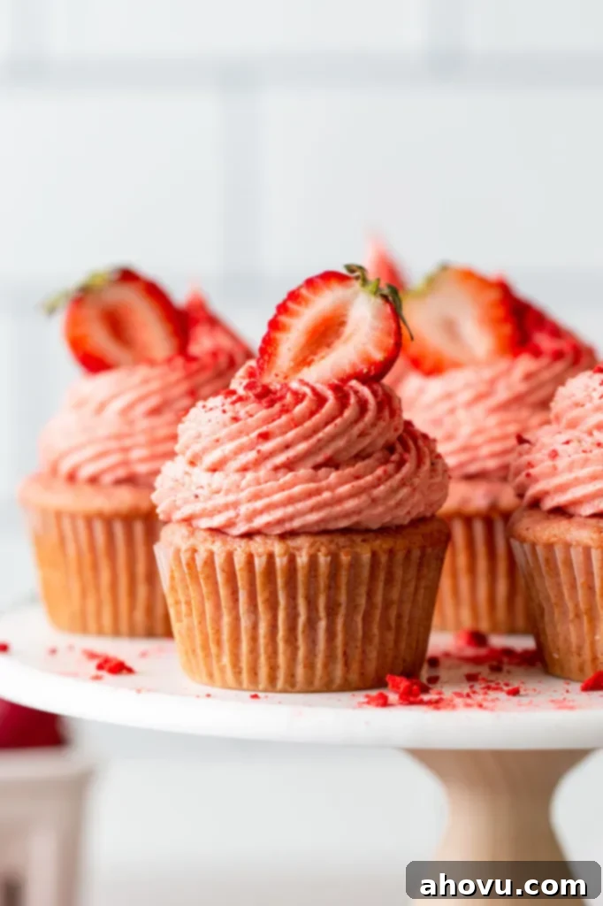 A beautiful side view of perfectly baked and frosted homemade strawberry cupcakes arranged elegantly on a cake stand, ready to be enjoyed.