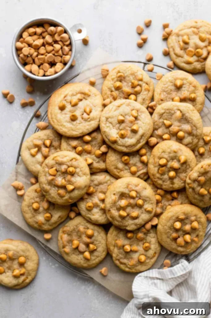 Golden Butterscotch Bites 2 An overhead view of butterscotch cookies piled on a wire cooling rack. A dish of butterscotch chips rests on the side.