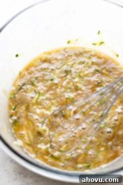 An overhead view of the wet ingredients for zucchini bread muffins in a mixing bowl.