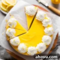 An overhead view of a lemon cheesecake topped with lemon curd and whipped cream. The cheesecake has been partially sliced and one slice has been removed.