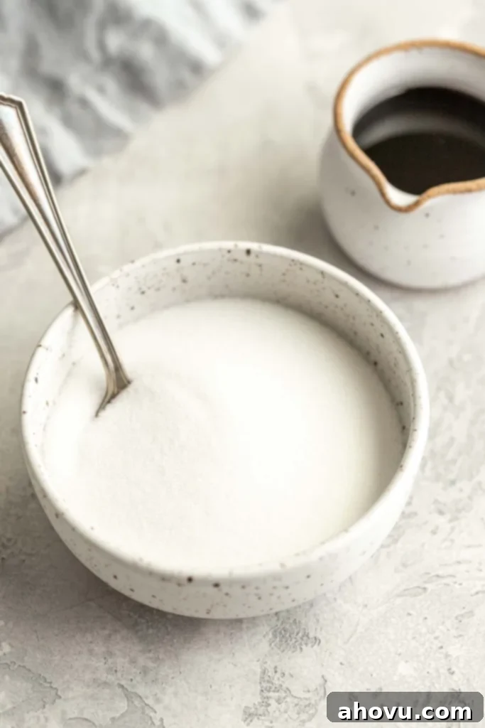 A bowl of granulated sugar next to a small jug of molasses. 