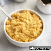 A bowl of light brown sugar with a spoon resting in it. A small container of molasses sits in the background.