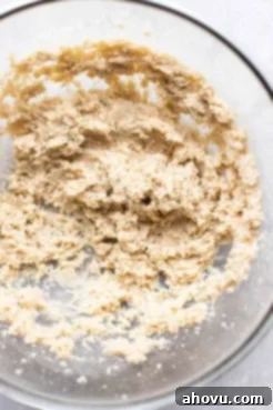 An overhead view of a glass mixing bowl containing perfectly creamed butter and sugars, light and fluffy, ready for the next step in making banana cookies.