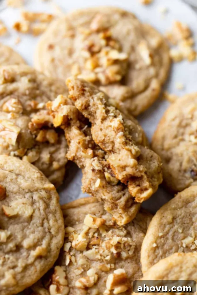 A beautifully composed close-up shot of a banana cookie, perfectly split in half, revealing its soft, moist interior and resting among a delightful pile of other cookies, ready to be enjoyed.