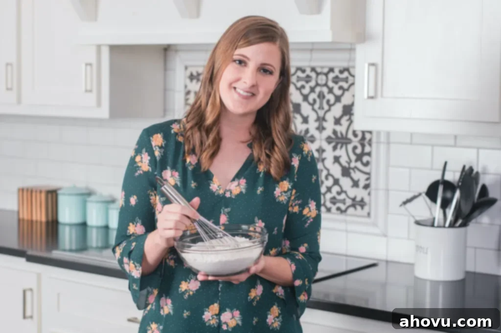 Kitchen Chronicles and Personal News 2 A picture of Danielle, the author, in a vibrant green shirt, smiling while holding a mixing bowl filled with dry ingredients and a whisk, ready for baking.