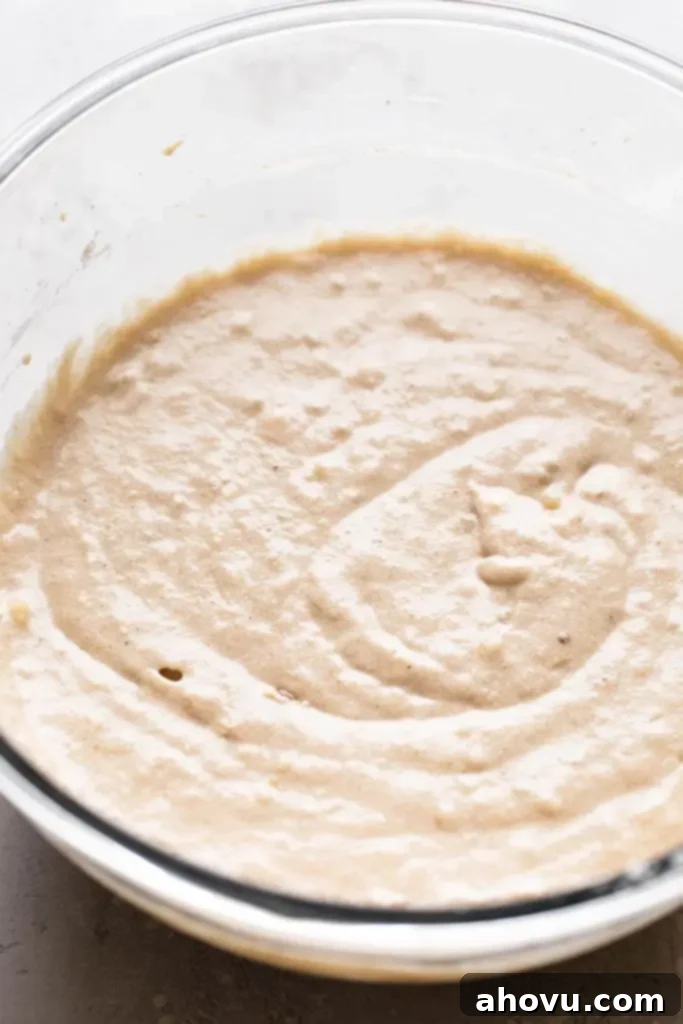 A glass mixing bowl full of banana cupcake batter. 
