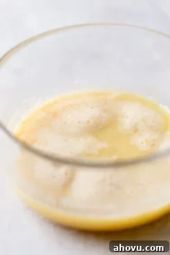 A glass mixing bowl holding cooled browned butter.