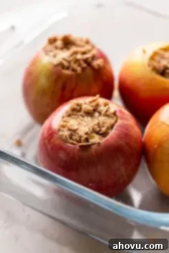 Whole apples in a glass baking dish that have been stuffed with a cinnamon oat mixture.