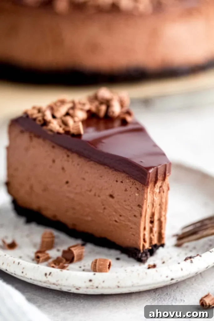 A slice of chocolate cheesecake with a bite missing on a white speckled plate. 