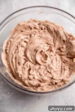 An overhead view of a chocolate cheesecake filling in a glass mixing bowl.