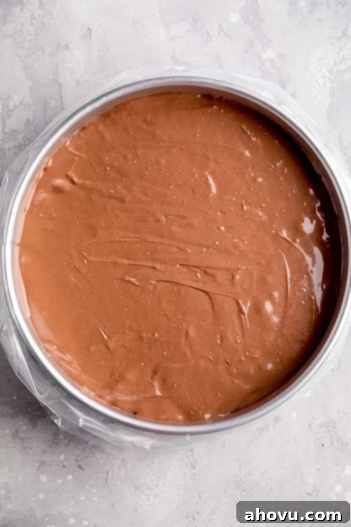 An overhead view of an unbaked chocolate cheesecake in a springform pan that's been placed in an oven bag.