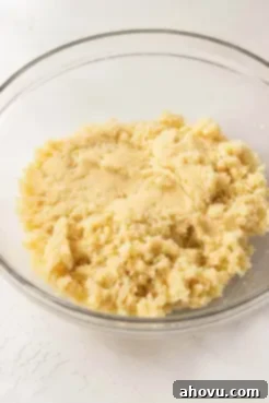 A mixture of vanilla cake and buttercream frosting in a glass mixing bowl.