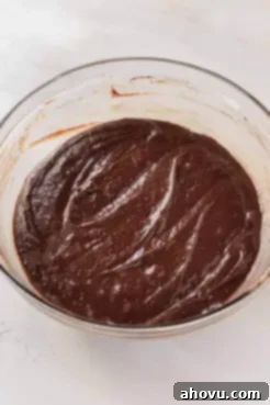 A glass mixing bowl full of chocolate cake batter.