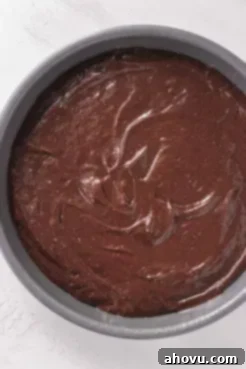 An overhead view of chocolate cake batter in a metal baking tin.