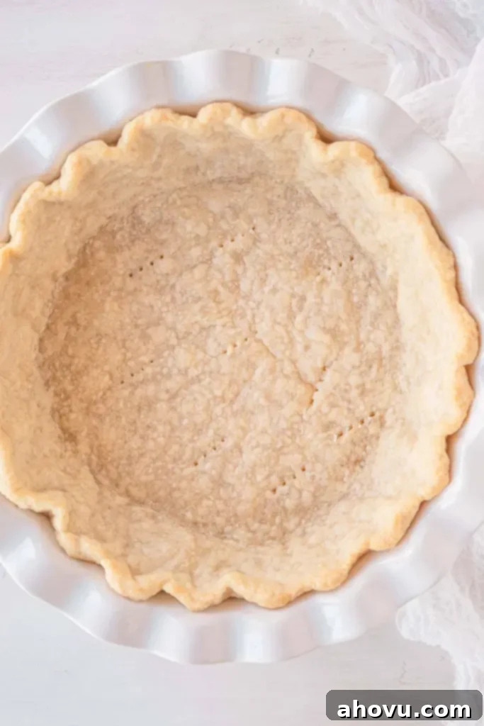An overhead view of a partially baked pie shell in a pie plate. 