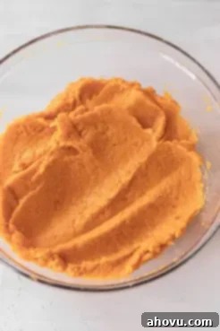 An overhead view of mashed sweet potatoes in a glass mixing bowl.