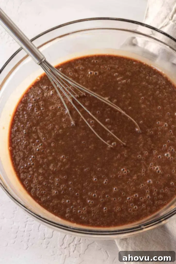 Texas sheet cake batter whisked together in a glass mixing bowl.