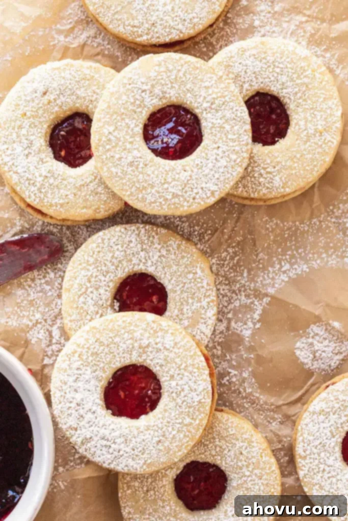 Peekaboo Jam Cookies 5 An overhead shot featuring a delightful pile of freshly baked raspberry Linzer cookies, beautifully dusted with powdered sugar, ready for serving.
