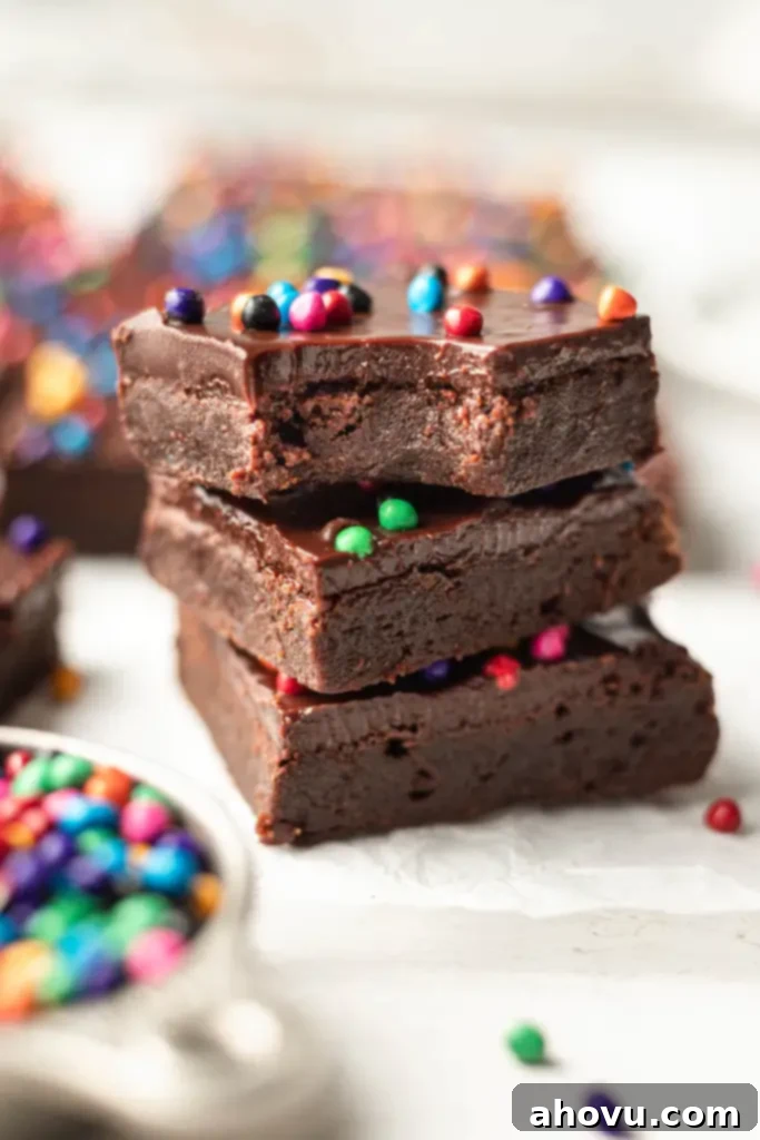 A stack of three homemade Cosmic Brownies. The top brownie is missing a bite. 