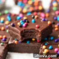Several cosmic brownies sliced on a piece of parchment paper. One brownie has a bite taken out and is sitting on top of another brownie.