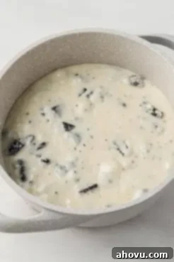 An overhead view of a smooth, glossy white chocolate and sweetened condensed milk mixture in a saucepan after melting, showcasing the perfectly combined fudge base ready for Oreos.
