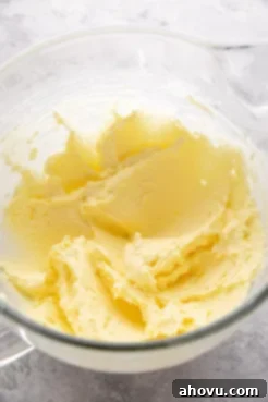 Butter, sugar, and egg yolks mixed together in a large glass mixing bowl.
