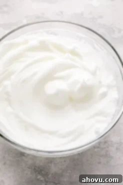 Egg whites beaten to stiff peaks in a glass mixing bowl.