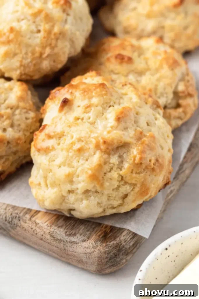 No-Fuss Fluffy Biscuits 5 Homemade drop biscuits arranged on a rustic wooden serving board, highlighting their golden-brown color and irregular, comforting shapes.