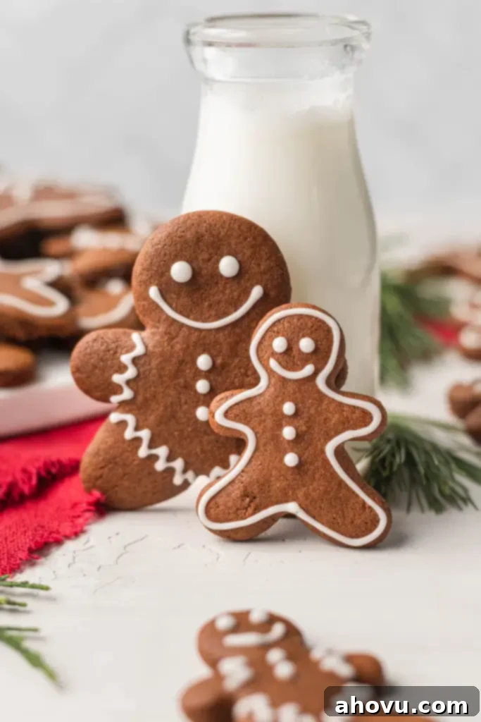 Deliciously soft gingerbread men cookies, perfectly iced, standing in front of a rustic glass pitcher of milk, ready for a festive treat.